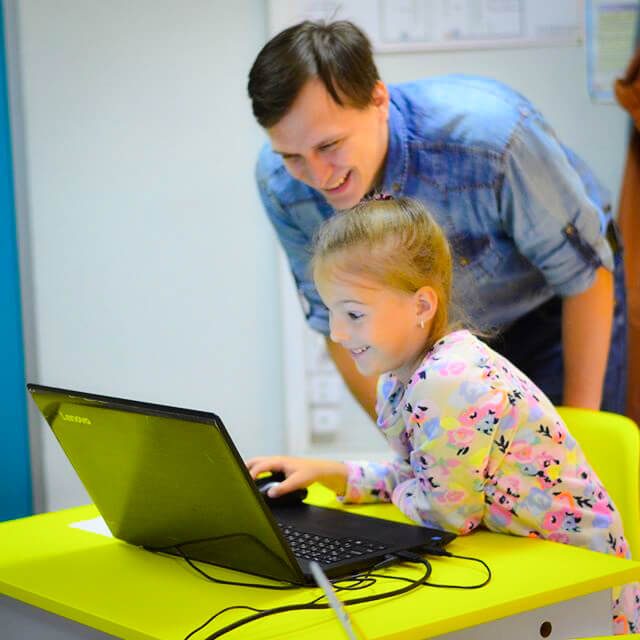 Счастливая девочка за ноутбуком с преподавателем